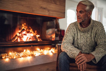Mature Man Sitting By Fire Place In Living Room