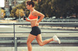© BalanceFormCreative - Female runner jogging on the city street by the traffic road.City environment.
