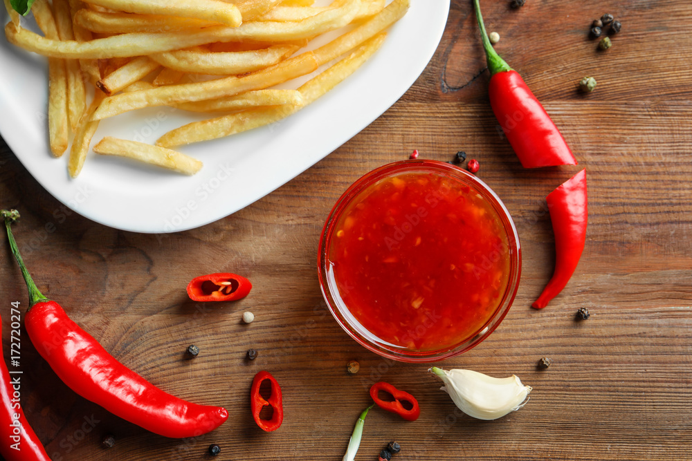 Chili sauce and plate with french fries on kitchen table