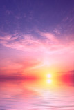 Fototapeta Zachód słońca - A purple sunset with a large sun with a small amount of clouds over the sea.