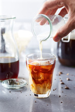 Hand Pouring Milk In Cold Brew Coffee