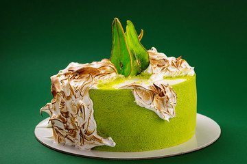 Wall Mural - Birthday cake with burned meringue and colored pear slices on green background