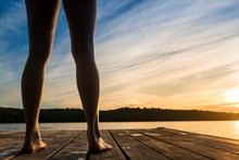 Woman About To Jump Into Warm Summer Cottage Lake At Sunset From Dock