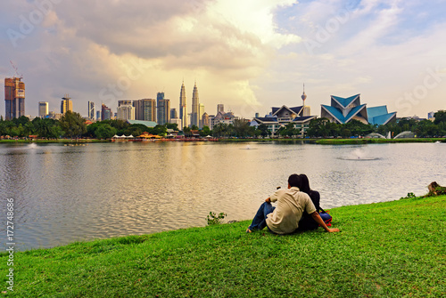 Fotografia, Obraz Unidentified couple at Taman Tasik Titiwangsa during sunset with Kuala Lumpur skyline, Kuala Lumpur, Malaysia