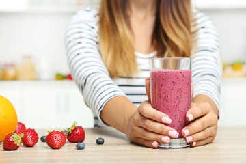 Young woman drinking smoothie in the kitchen