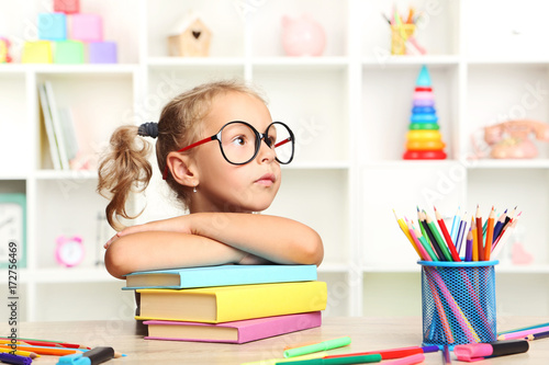 Little girl sitting with books at the table Poster Mural XXL
