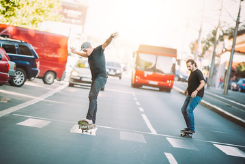 Two skateboarders riding skateboard slope on the city streets