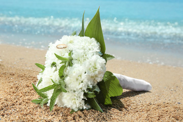 Wall Mural - Beautiful bouquet with golden rings on sand. Beach wedding concept