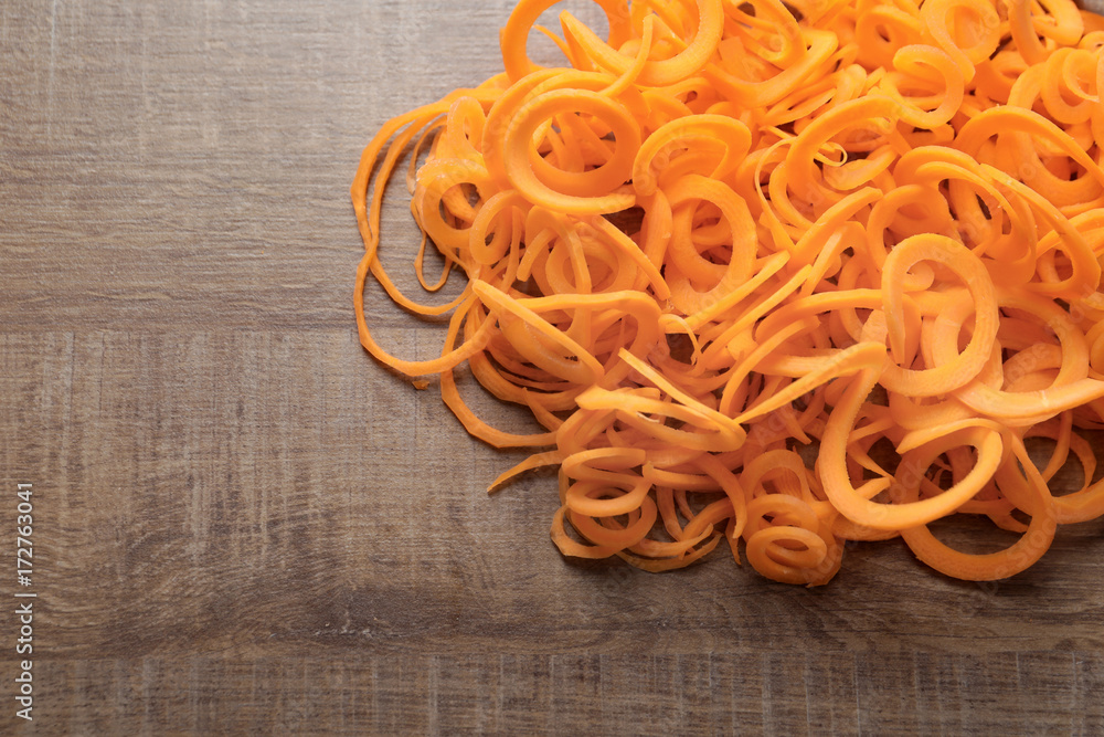 Raw carrot spaghetti on wooden background