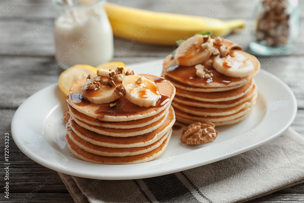 Plate with yummy banana pancakes on wooden table
