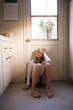 © Dina Marie Photography/Stocksy - Teenager Sitting On Kitchen Floor Up Against Door