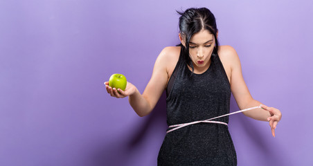 Canvas Print - Young woman measuring her waist with a tape measure