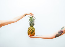 Two Arms Holding A Pineapple