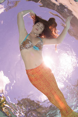 Wall Mural - A mermaid with and orange tail underwater.