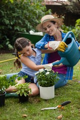 Wall Mural - Daughter assisting mother in watering potted plants