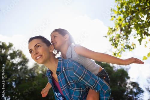 Fotografia Girl with arms outstretched enjoying piggyback ride on mother