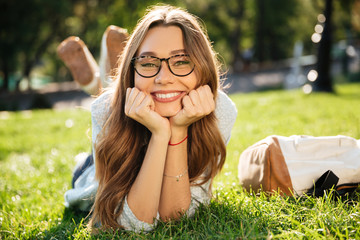 Sticker - Smiling brunette woman in eyeglasses lying on grass