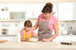 © Africa Studio - Cute little girl and her grandmother making dough on kitchen