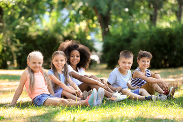 Wall Mural - Group of children sitting on grass in park