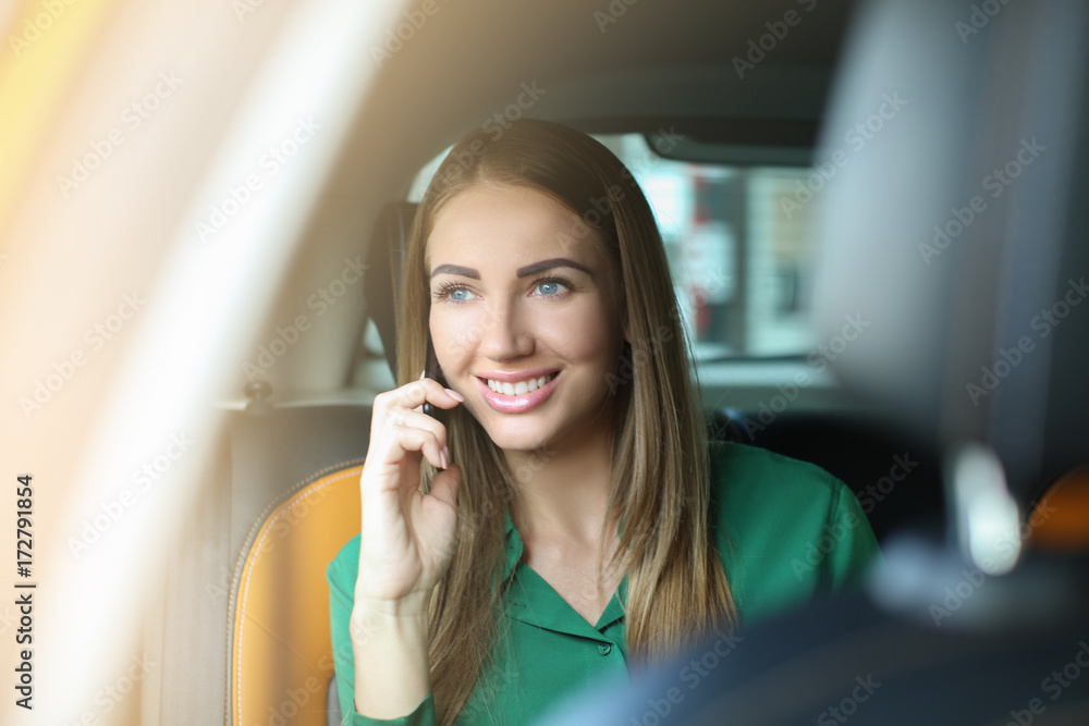Beautiful woman talking on phone while sitting in taxi