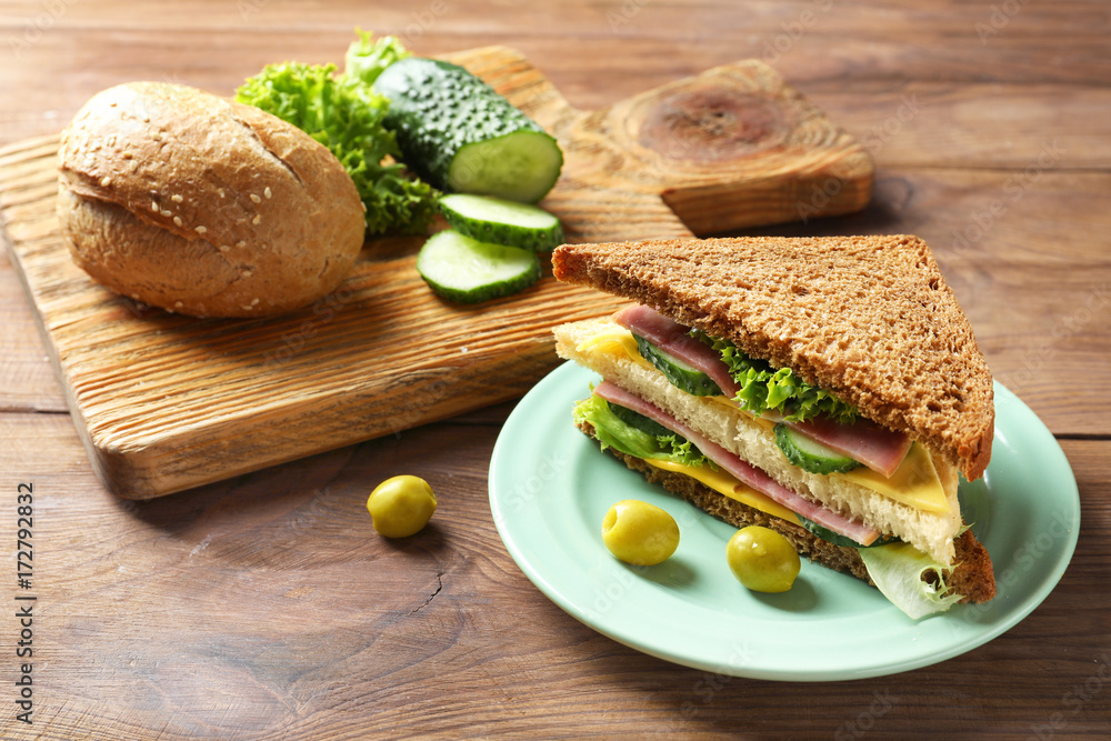 Plate of tasty sandwich with fresh cucumber on table