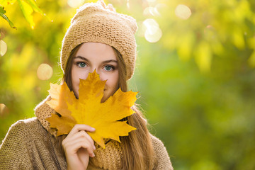 Young woman in knitted hat portrait with yellow maple leaf