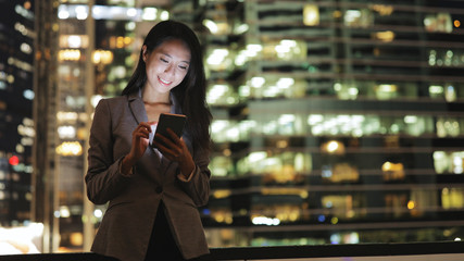 Business woman using mobile phone in city at night