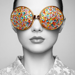 Portrait of beautiful young woman with colored glasses. Beauty fashion. Perfect make-up. Colorful decoration. Jewelry