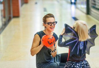 Sticker - smiling modern mother and daughter on Halloween at mall playing