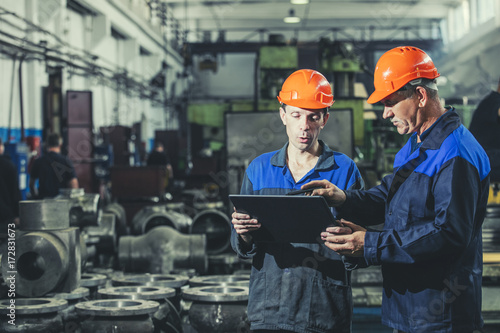 Cuadros en Lienzo Two workers at an industrial plant with a tablet in hand, working together manuf