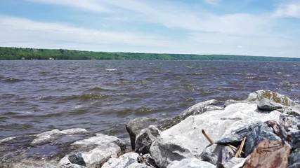 Wall Mural - Rocky shore with rocks on Saint Laurent or Lawrence river in Quebec, Canada in Portneuf pier during summer with water waves