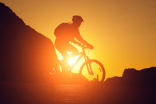 Silhouette Of A Young Woman On A Bicycle At Sunset