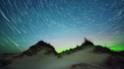 distant aurora borealis (northern lights) with comet like star trails