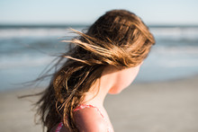 Young Woman Standing On The Beach With Wind In Her Hair