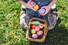 Child Kneeling In Grass With Easter Eggs