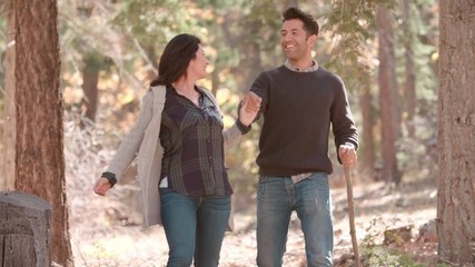 Wall Mural - Hispanic couple walk in forest holding hands, close up