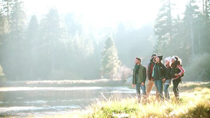 Wall Mural - A group of friends hiking near lake stop to admire the view