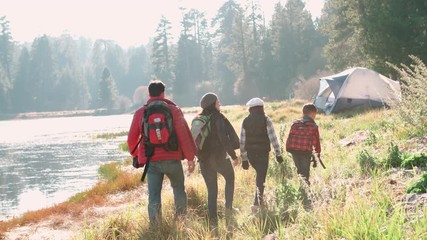 Wall Mural - Parents with two kids walking near a rural lake, back view