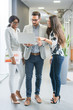 © Bojan - Group of three business people with laptop having informal meeting in office hall.