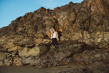 Young Woman Sitting On Seaside Rock Ledge