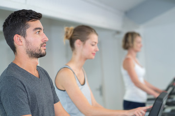 Wall Mural - three people cycling in a gym or fitness club