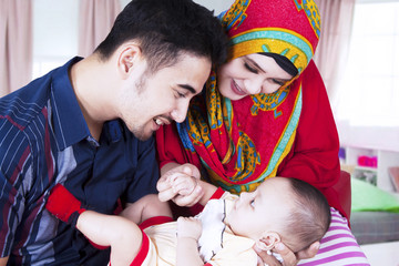 Wall Mural - Parents smiling with baby in living room