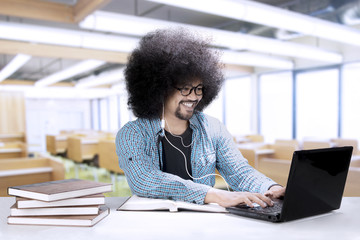 Wall Mural - Male student with a laptop and earphone