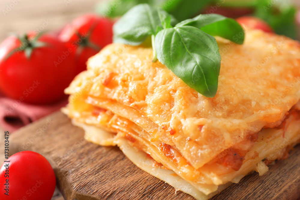 Portion of tasty lasagna on wooden board