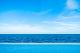 Fototapeta  - Infinity swimming pool with sea and ocean view on blue sky