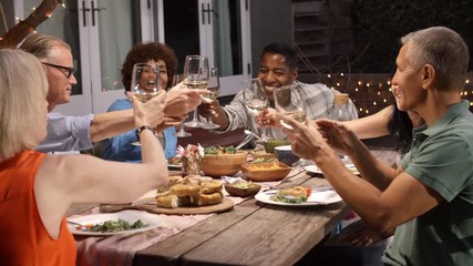 Wall Mural - Group Of Mature Friends Enjoying Outdoor Meal In Backyard