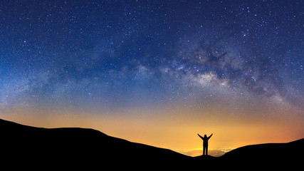 Wall Mural - panorama landscape with milky way, night sky with stars and silhouette of a standing sporty man with