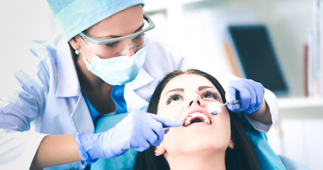 Wall Mural - Woman dentist working at her patients teeth