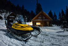 Snowmobile From House Chalets In Winter Forest With Snow In Light Moon And Starry Sky