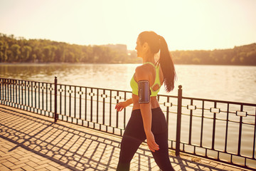 a sporty girl is walking in a sporting walk in the park by the lake.
